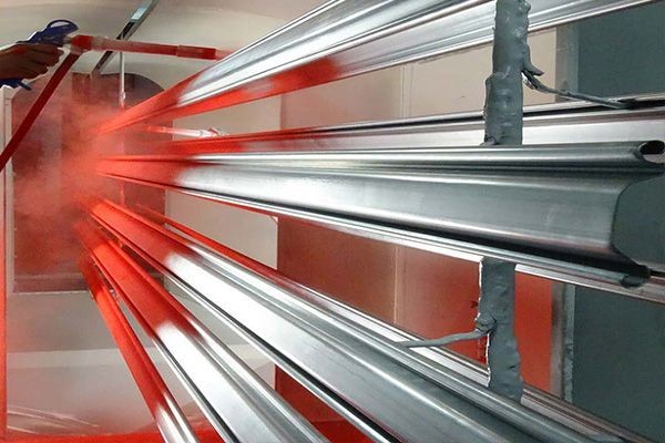 Application de poudre rouge sur des profilés métalliques en cabine