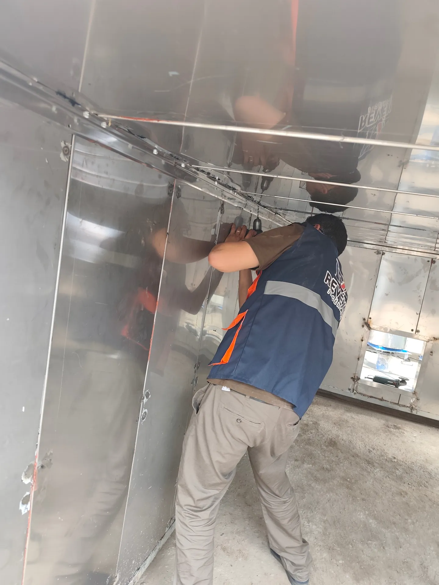 Technicien REVEXIA assemblant les panneaux inox d’un four en atelier