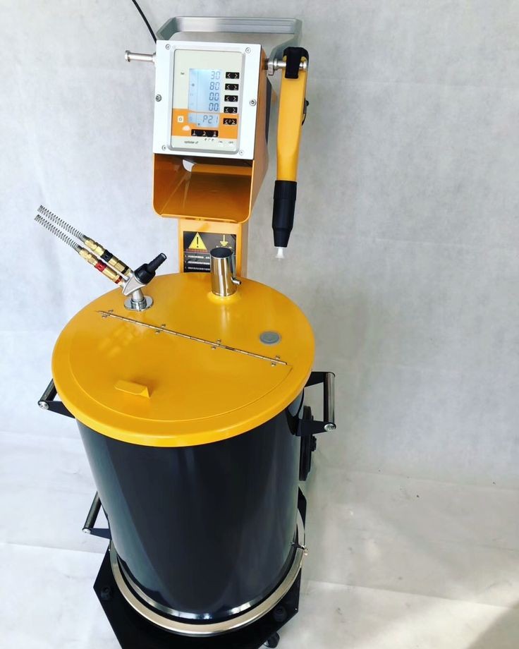 Équipement de poudrage électrostatique avec cuve de poudre, panneau de commande et pistolet d'application manuel.